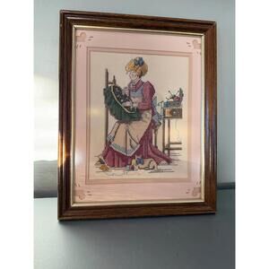 Vintage framed cross stitch art of woman sewing
